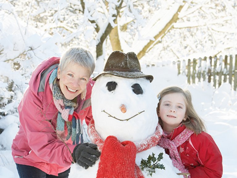 Grandmother and grandchild building a snowman
