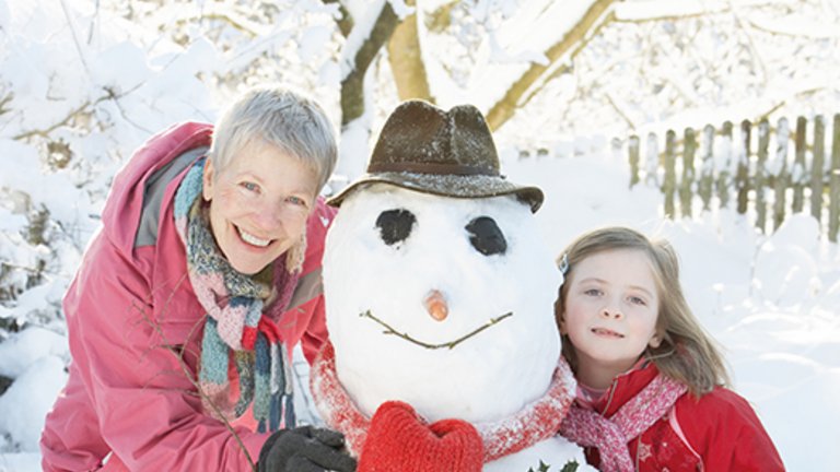 Grandmother and grandchild building a snowman