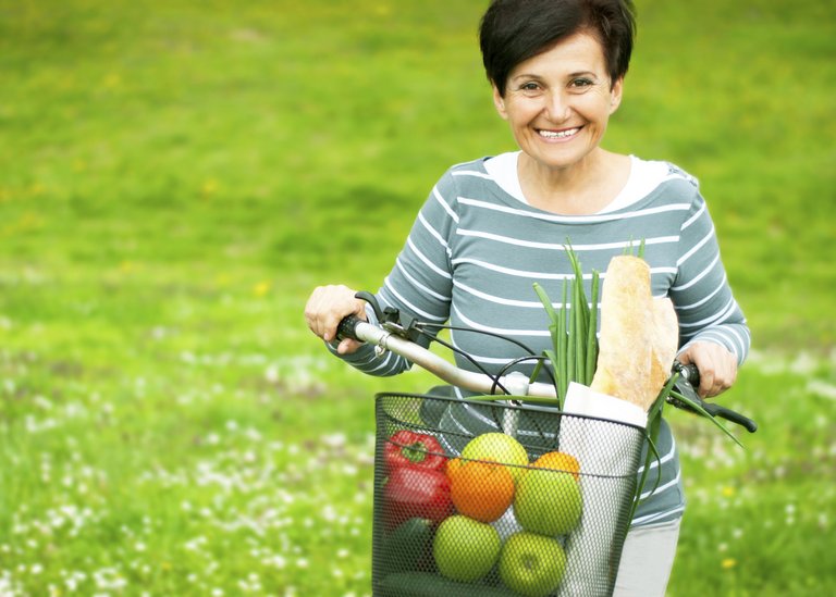 [Translate to COM English:] Woman on a bike with healthy food in the basket