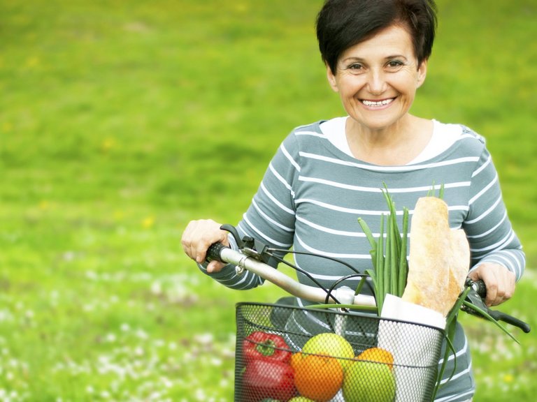 Woman on a bike with healthy food in the basket