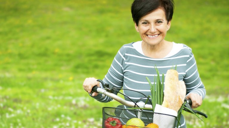 Woman on a bike with healthy food in the basket